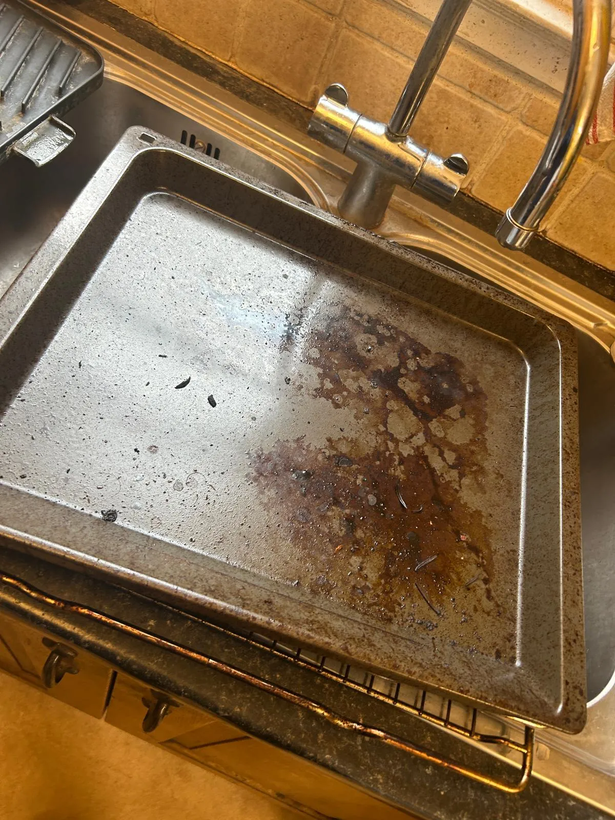 Burnt and greasy oven tray before cleaning